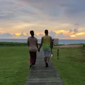 A man and woman holding hands while walking on the boardwalk.